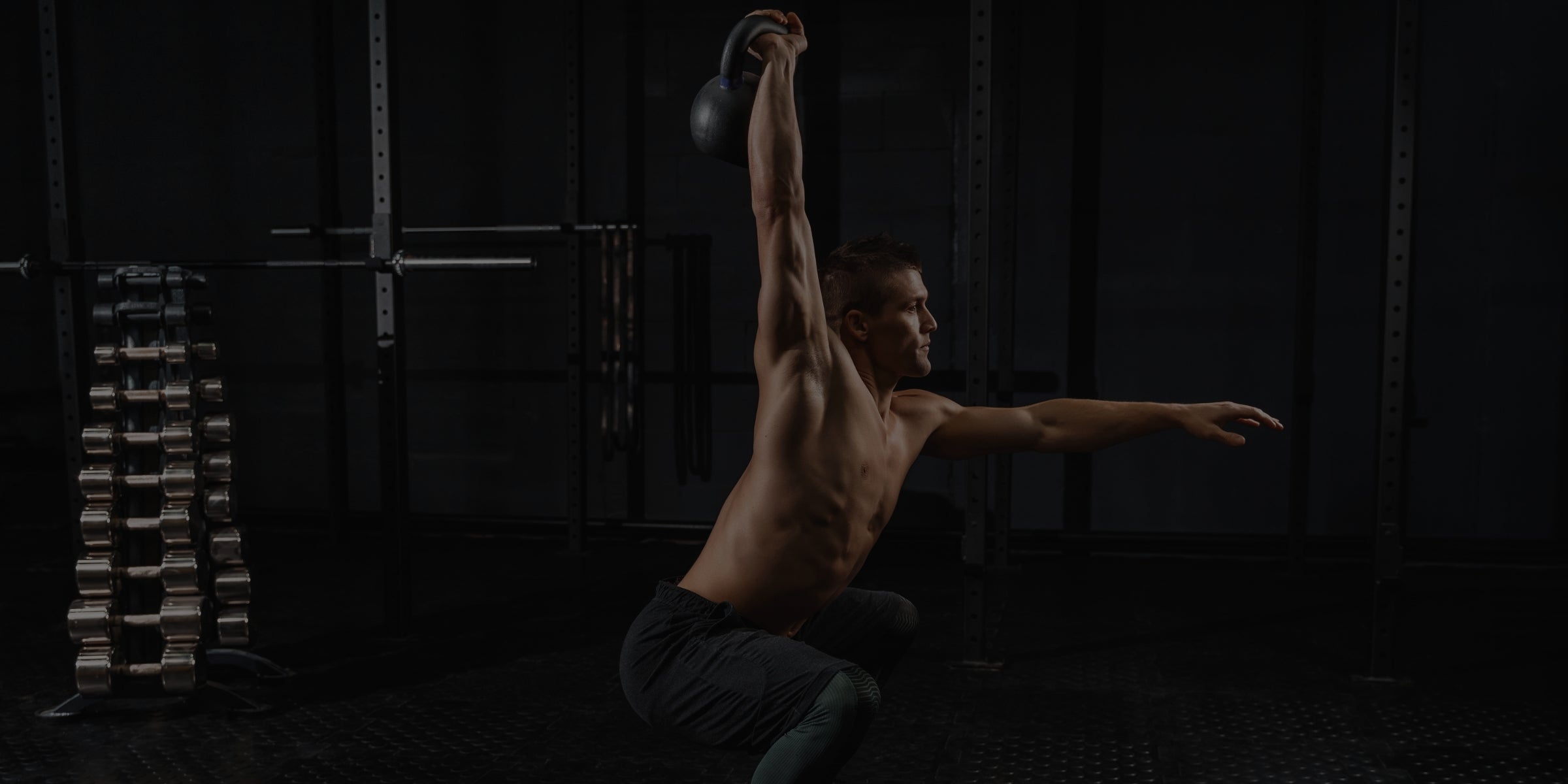 Man lifting a kettlebell in a dark indoor setting
