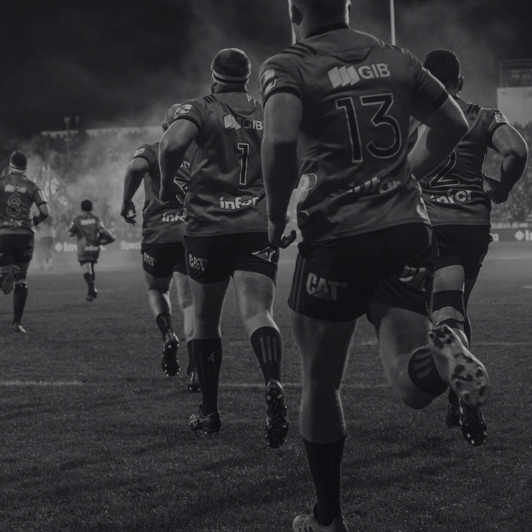 Black and white image of rugby players running on a field