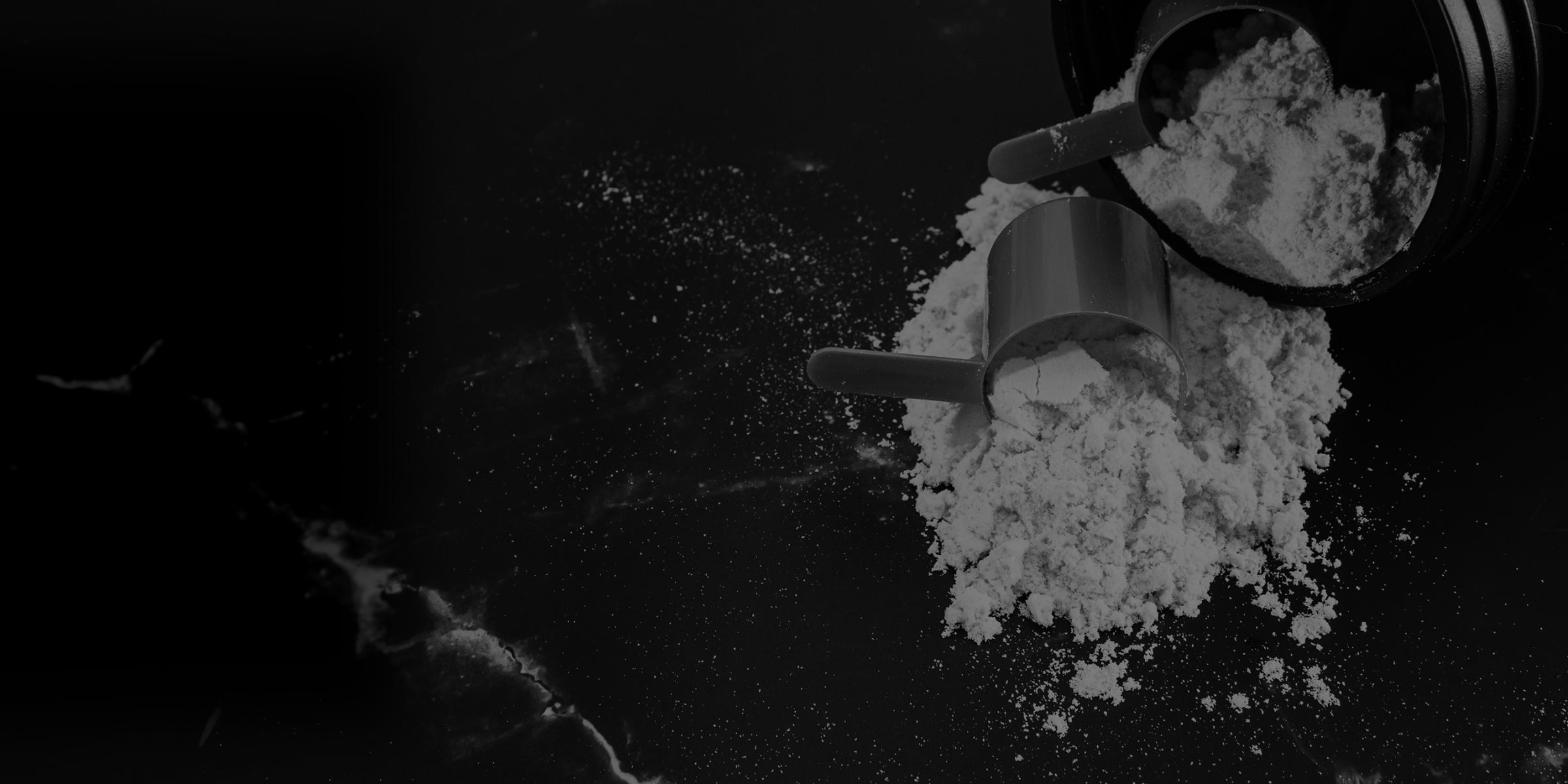 Metal scoop with white powder on a dark surface