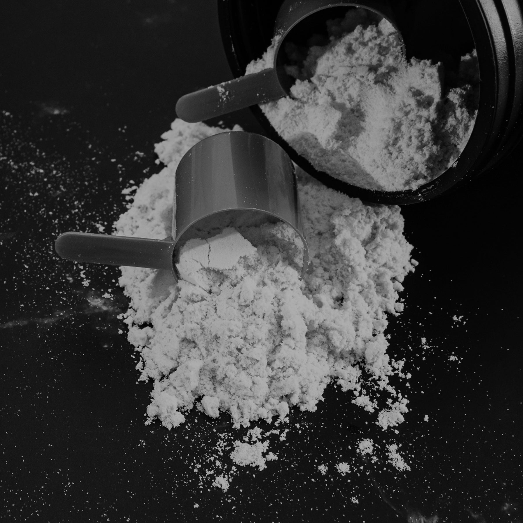 Close-up of a scoop of protein powder being poured onto a dark surface